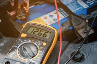 Tamirci voltaj seviyesini kontrol etmek için voltaj ölçer kullanıyor.