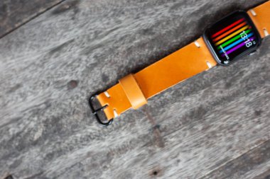 Açık kahverengi deri saat kayış ahşap üzerinde çalışıyor.