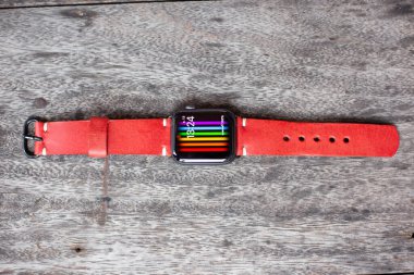 Hakiki kırmızı kahverengi deri saat kayışlı el işi ahşap arka plan üzerinde çalışıyor.