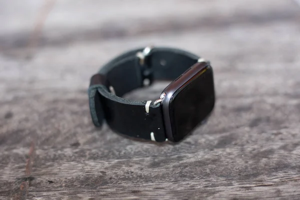 Black leather watch strap hand craftmanship working on wood background