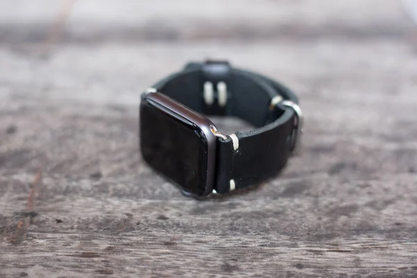 木製の背景で作業ブラックレザー腕時計ストラップハンドクラフトマンシップ — ストック写真