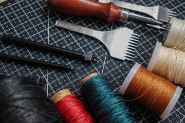 Metal aletlerle çalışan renkli deri iplik işi.