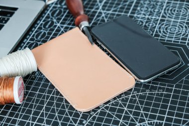 Sebze bronzlaştırılmış deri telefon kılıfı. El yapımı ve iplik ve alet ile çalışan el işi bir gemi.