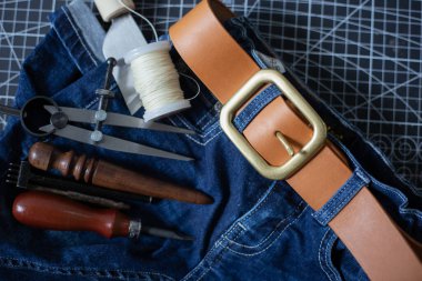 Deri kemer pirinç tokası, kotun üzerinde ustalıkla çalışan bir aletle.