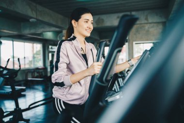 Güzel Asyalı kadınlar spor salonunda eliptik egzersiz yapıyorlar. Özel fitness salonunda.
