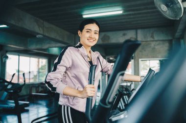 Güzel Asyalı kadınlar spor salonunda eliptik egzersiz yapıyorlar. Özel fitness salonunda.