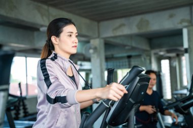Güzel Asyalı kadınlar spor salonunda eliptik egzersiz yapıyorlar. Özel fitness salonunda.