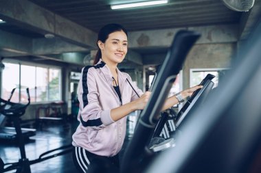 Güzel Asyalı kadınlar spor salonunda eliptik egzersiz yapıyorlar. Özel fitness salonunda.