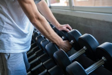 Spor adamı halterini kaldırıyor. Spor salonunda oturuyor. Sosyal mesafeler.