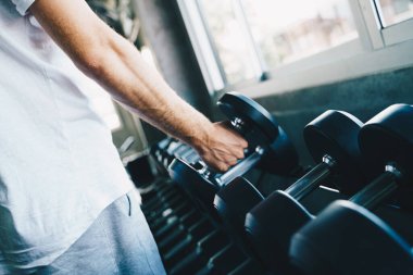 Akıllı sporcu spor salonunda dambılı kaldırıyor. Aktivite eli kapalı.