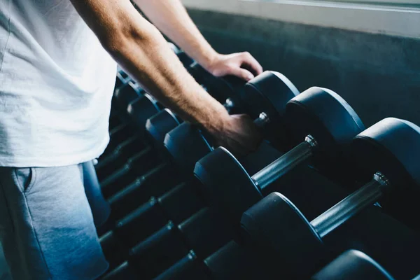 Smart sport man lifting dumbbell up in fitness gym wellnes activity hand close up