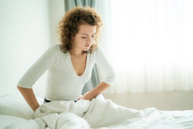 Karın ağrısından muzdarip genç bir kadın sabah uyanırken karın ağrısı çekiyor.