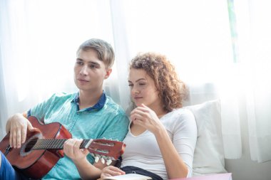Love couple enjoy together with guitar on bed white room Happy men and women