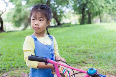 Şehir parkındaki bisikletli sevimli kız egzersizi.