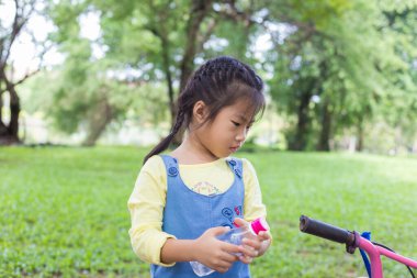 Şehir parkındaki bisikletli sevimli kız egzersizi.