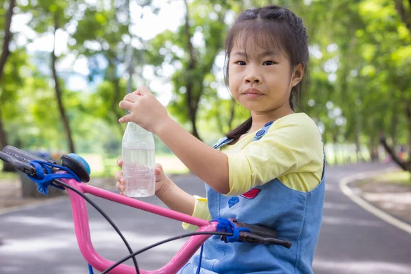 Şehir parkındaki bisikletli sevimli kız egzersizi.