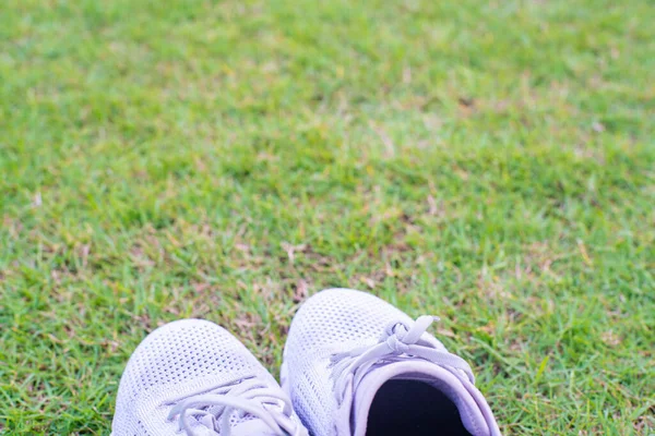绿色足球场草地上的白色跑鞋 — 图库照片