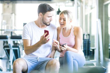 İki erkek spor salonunda çalıştıktan sonra akıllı telefon konuşmaları yapıyor.