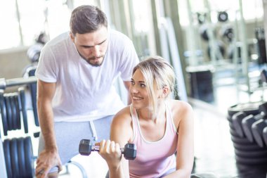 Eğitmen kadınlara spor salonunda halter kaldırmayı öğretiyor.