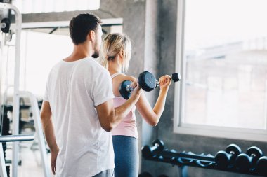 Eğitmen kadınlara spor salonunda halter kaldırmayı öğretiyor.