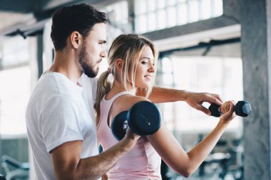 Eğitmen kadınlara spor salonunda halter kaldırmayı öğretiyor.