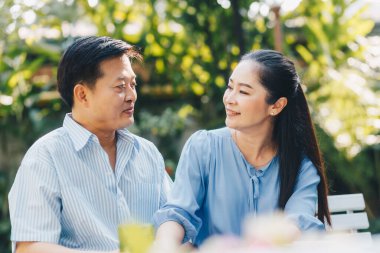 Yaşlı bir emekli çift parkta oturmuş, aşk konsepti ümidiyle ahşap bankta konuşuyor.