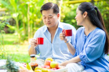 Yaşlı bir emekli çift parkta oturmuş, aşk konsepti ümidiyle ahşap bankta konuşuyor.