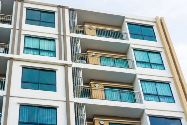 Mavi pencereli, düz ve ev arka planlı modern gayrimenkul apartmanı.