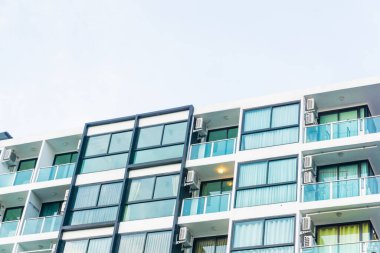 Mavi pencereli, düz ve ev arka planlı modern gayrimenkul apartmanı.