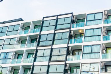 Mavi pencereli, düz ve ev arka planlı modern gayrimenkul apartmanı.
