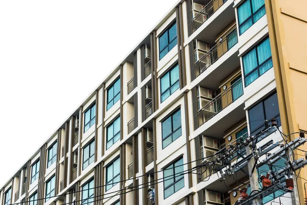 Mavi pencereli, düz ve ev arka planlı modern gayrimenkul apartmanı.