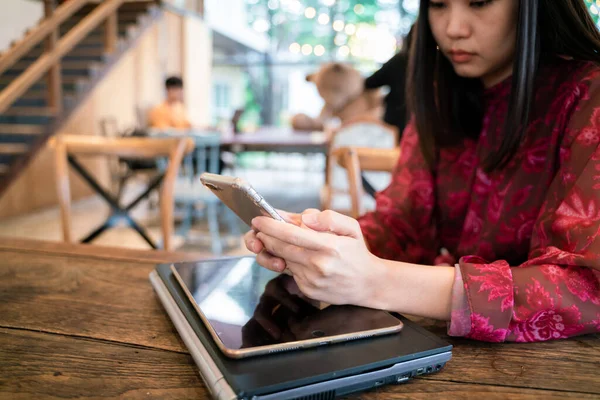 Kadınlar kafeteryada otururken bilgisayarlı akıllı telefon kullanırlar.