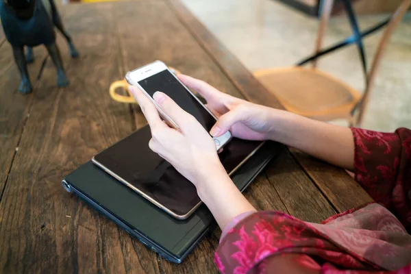 Kadınlar kafeteryada otururken bilgisayarlı akıllı telefon kullanırlar.