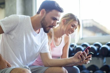 İki erkek spor salonunda çalıştıktan sonra akıllı telefon konuşmaları yapıyor.
