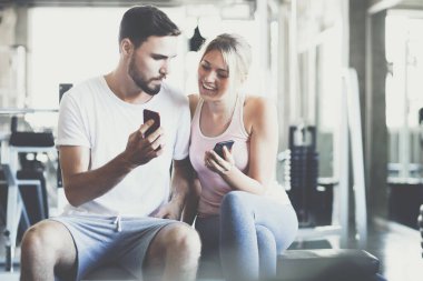 İki erkek spor salonunda çalıştıktan sonra akıllı telefon konuşmaları yapıyor.