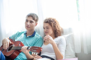 Love couple enjoy together with guitar on bed white room Happy men and women