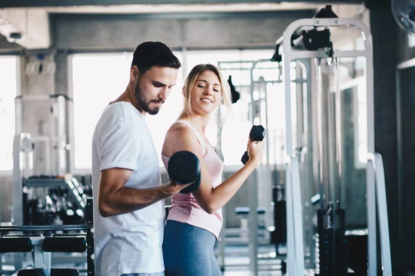 Instructor man teach women lifting up dumbbell in sport gym healthy couple exercise