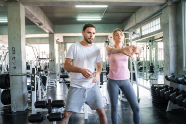 Couple stretch body before exercise in sport gym together private trainer healthy lifestyle