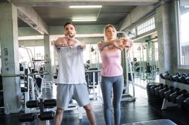 Couple stretch body before exercise in sport gym together private trainer healthy lifestyle