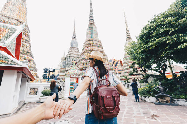 Asian women leading man hand follow travel in buddhist temple couple relationship Bangkok Thailand