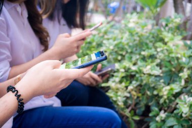 Bir grup Asyalı bayan arkadaş açık havada akıllı telefon kullanıyor. Yakın çekim.