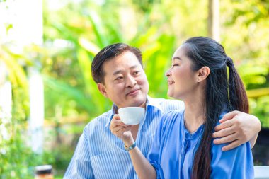 Yaşlı çift kahve içiyor ve parkta konuşuyor, Asyalı çift.