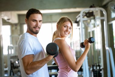 Spor salonunda halter kaldıran bir çift spor salonundaki kadınlara sağlıklı bir yaşam tarzı sunuyor.