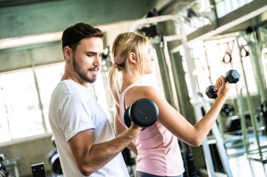 Spor salonunda halter kaldıran bir çift spor salonundaki kadınlara sağlıklı bir yaşam tarzı sunuyor.