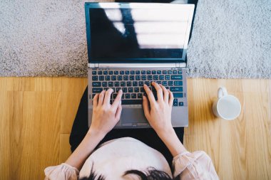 Üst görüşlü kadınlar dizüstü bilgisayarda oturup kahve fincanı kullanıyor.