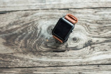 Deri kahverengi saat askısı ve ahşap arka planda ustalıkla yapılmış.