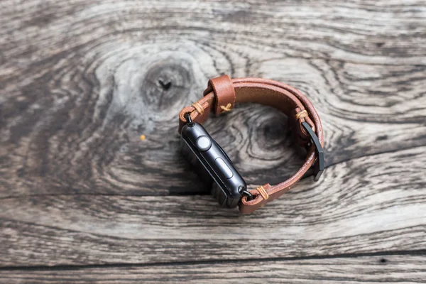 木製の背景にスマートウォッチクラフトマンシップとレザーブラウンの腕時計ストラップ — ストック写真