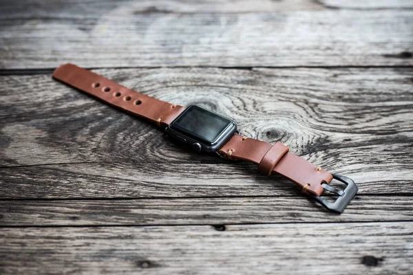 Leather brown watch strap  with smartwatch craftmanship on wooden background