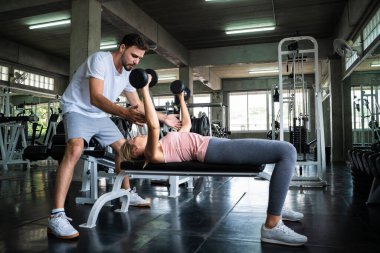 Erkekler spor salonunda kadınlara halter kaldırmayı öğretir.