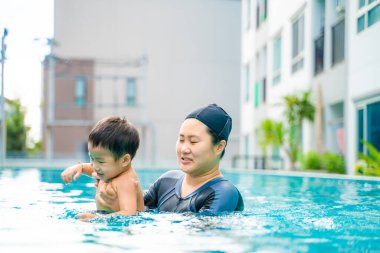 Anaokulu güneşli annem yüzme antrenmanında yüzme havuzunda yüzüyor.